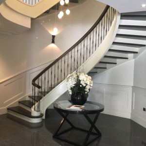 Traditional styled oak curved staircase, closed riser hand painted strings with matching oak treads and handrails and a basket style iron spindle with continuous handrails Traditional styled oak curved staircase