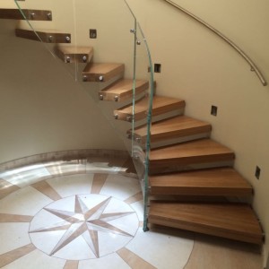 Helical floating staircase with chunky curved oak treads and curved frameless glass balustrade Helical floating staircase with chunky curved oak treads and curved frameless glass balustrade