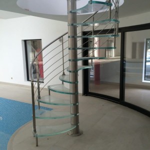Glass spiral stair in a swimming pool and gym with double anti slip etched glass and stainless steel traversal rods and newel posts Glass spiral stair in a swimming pool and gym